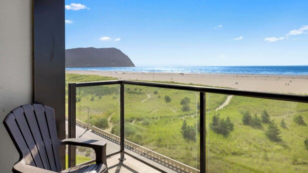 A balcony with a view of a beach and a grassy landscape. - Sand & Sea (402) Water's Edge Panoramic Views (Seaside)