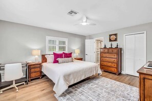 Quarto com cama, mesas de cabeceira, cômoda, escrivaninha e cadeira.