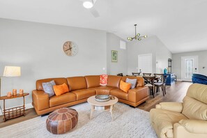 A modern living room with a brown leather sofa, a round coffee table, and a beige armchair. - Pet-Friendly Home 4 Miles to Beach & Shops (Naples)