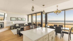 Una cuina moderna amb una illa gran, zona de menjador amb caires i vista a la platja.