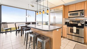 Una cocina moderna con una isla grande, electrodomésticos de acero inoxidable y vistas al exterior.
