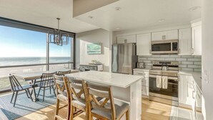 A modern kitchen with a large island, stainless steel appliances, and a view of the ocean. - Sand & Sea (508) Salt Life - Lux Beachfront w Pool (Seaside)