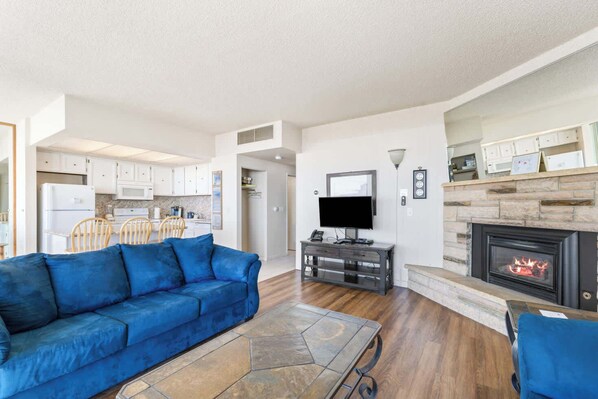 A modern living room with a blue sofa, a TV, and a fireplace.