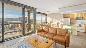 A modern apartment with a large balcony, a leather sofa, a dining area, and a kitchen. - Sand & Sea (618) Seaside Panorama -Cozy Beachfront (Seaside)