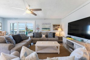 A living room with a sofa, coffee table, TV, and a ceiling fan.