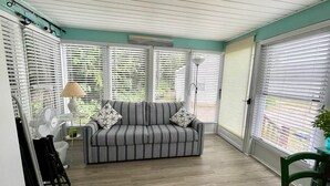 Una habitación con un sofá a rayas, una lámpara, un ventilador y una silla.