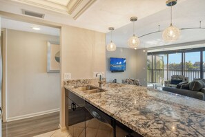 A modern kitchen with a large island, built-in dishwasher, and pendant lighting. - Siesta Key Condo, Private Beach Access & Water Views - Midnight Cove II 122F (Siesta Key)