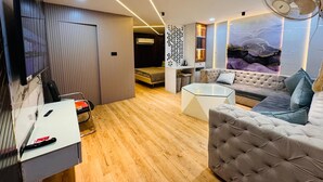 Una sala de estar moderna con un sofá, una mesa de centro de vidrio, un televisor montado en la pared y un ventilador de techo.