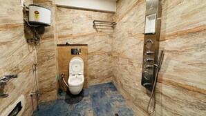 Un baño moderno con pared de mármol, inodoro, ducha y calentador de agua.