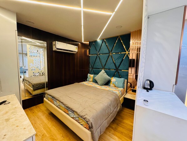 A modern bedroom with a bed, wooden floor, and a decorative headboard.