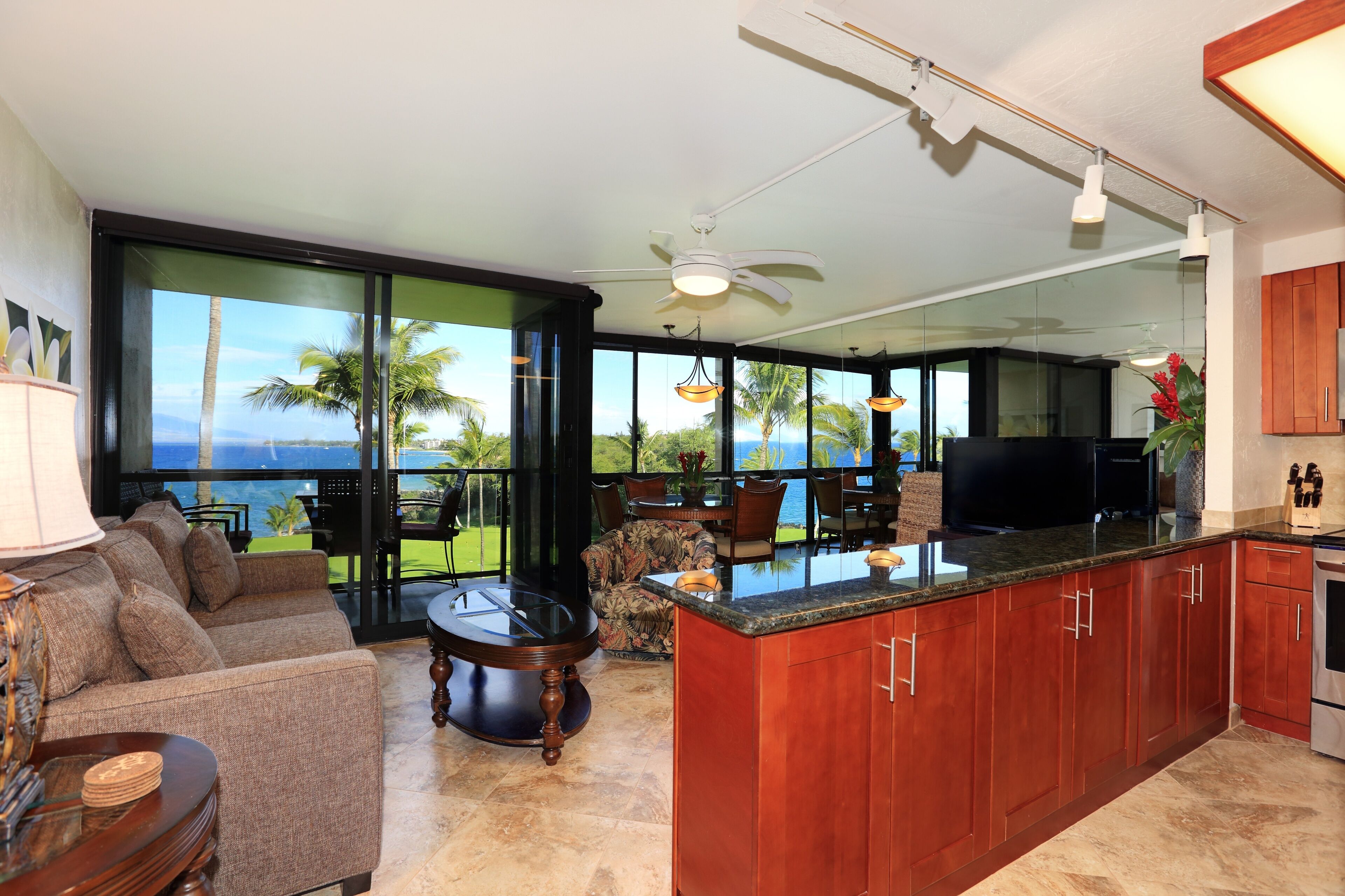 A modern kitchen with a large island, dining area with chairs, and a view of the ocean through large windows.