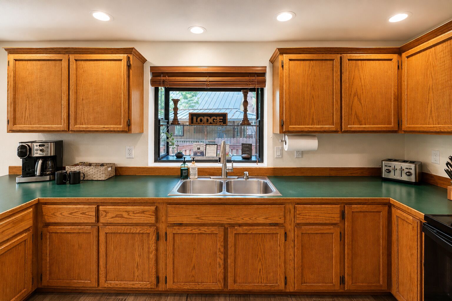 A kitchen with wooden cabinets, a stainless steel sink, a coffee maker, and a toaster.