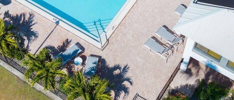 An aerial view of a swimming pool area with lounge chairs and palm trees.
