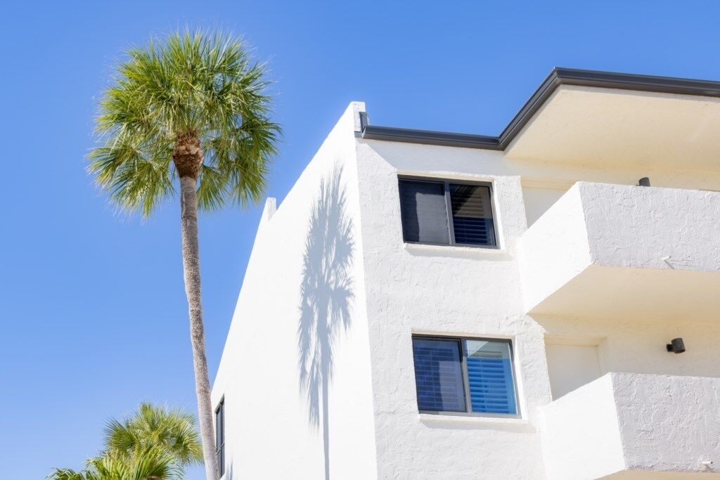 A white building with two windows and a balcony.
