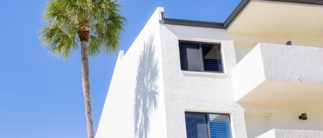 A white building with two windows and a balcony.