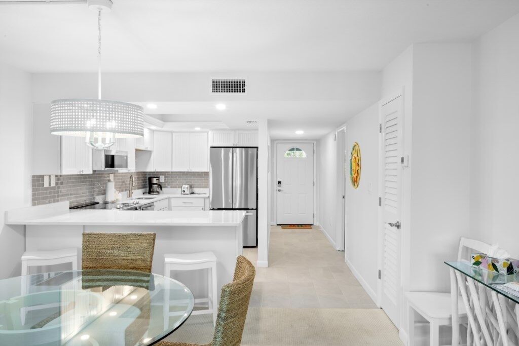 A modern kitchen with white cabinetry, stainless steel appliances, and a glass dining table.