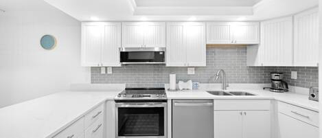 A modern kitchen with white cabinetry, a stainless steel oven, a dishwasher, and a microwave.