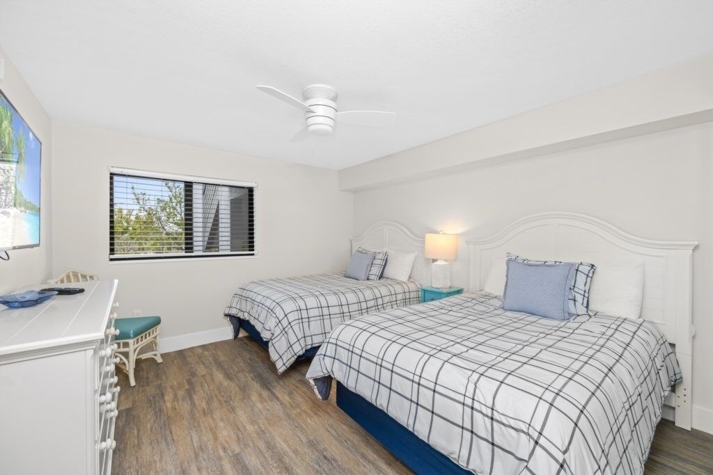 A bedroom with two beds, a desk, and a chair.