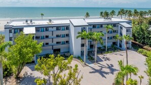 Un hotel de varios pisos con piscina en la azotea, rodeado de palmeras y vistas a la playa.