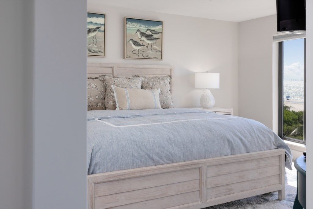 A bedroom with a large bed, a nightstand, a lamp, and artwork on the wall.