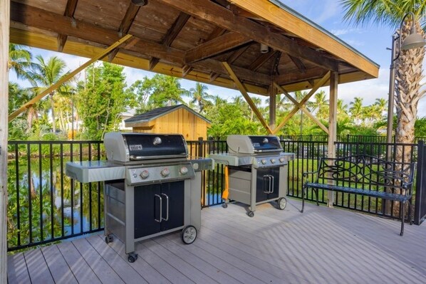 An outdoor patio with two portable grills and a bench.