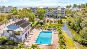 Un resort con piscina, palmeras y vista al océano.