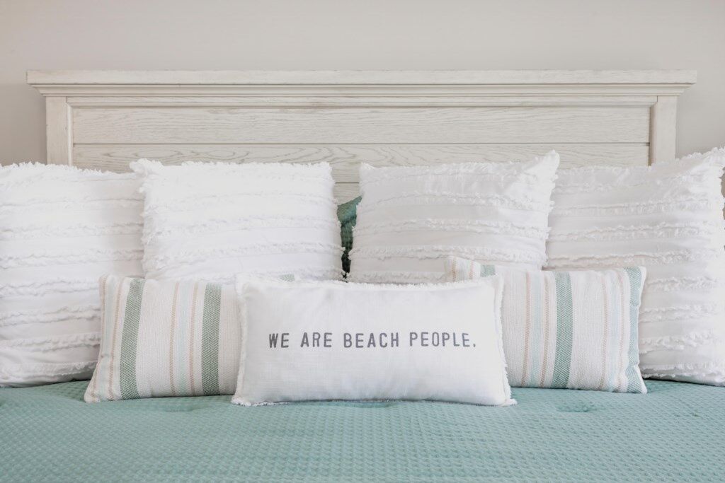 A bed with white and striped pillows and a teal bedspread.