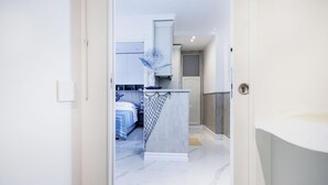 Une chambre moderne avec un lit, un petit bureau et une salle de bain équipée d’un lavabo.