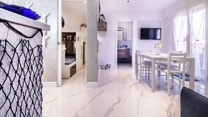 Un intérieur moderne comprenant un coin repas, une cuisine et une chambre dotée d’une armoire intégrée.
