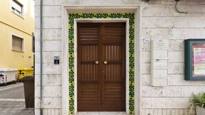 Una puerta doble de madera con un borde decorativo verde, un buzón y el número 183.