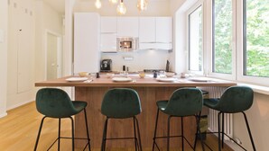 Una cocina moderna con una isla central, armarios blancos y un amplio ventanal con vistas a zonas verdes.