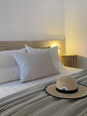 A neatly made bed with white pillows and a woven hat on the bedspread. - Aristotelia Gi Domes - Luxury Private Pool Retreat (Olympiada)