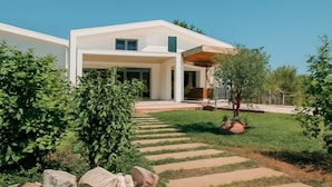 Une maison moderne dotée d’un grand porche à l’avant, d’un chemin en pierre menant à l’entrée et d’une pelouse bien entretenue.