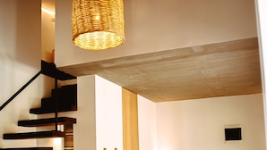 Un intérieur moderne avec un escalier, un canapé, une table basse et un luminaire suspendu.