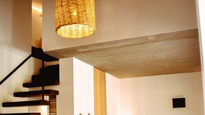A modern interior with a staircase, a sofa, a coffee table, and a hanging light fixture.