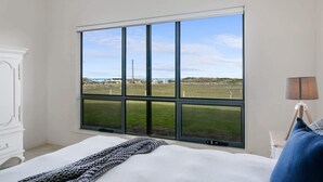 Une chambre avec une grande fenêtre, un lit, une lampe et une armoire.