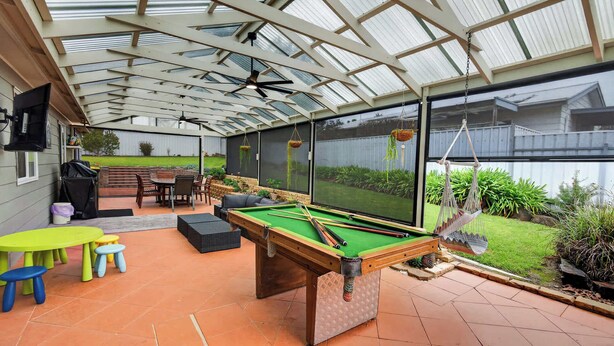 A pool table in a covered outdoor area with a patio table and chairs, and a view of a backyard through a large window. - 91 On the Rocks 91 Port Elliot Rd Hayborough Chiton (Hayborough)
