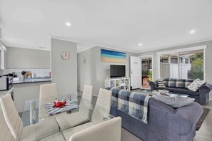 A modern living space with a dining area, a sofa, and a television.