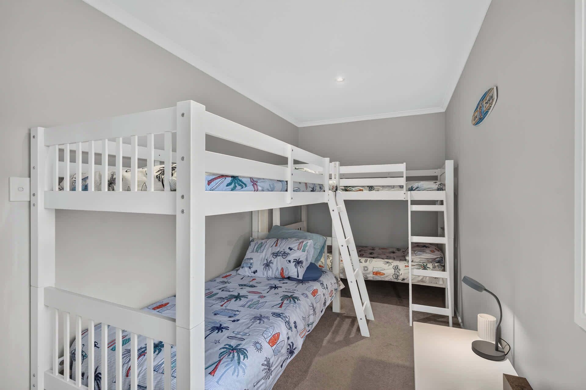 A bunk bed room with a ladder, a desk, and a lamp.