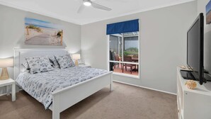 A bedroom with a bed, a ceiling fan, a window with a view of the outdoors, and a television on a stand. - 91 On the Rocks 91 Port Elliot Rd Hayborough Chiton (Hayborough)