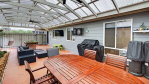 A covered outdoor patio with a wooden table and chairs, a ceiling fan, and a dartboard. - 91 On the Rocks 91 Port Elliot Rd Hayborough Chiton (Hayborough)