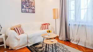 A cozy living room with a white sofa, a small coffee table, and a floor lamp. - Cozy Studio in the Center of Zagreb (Zagreb)