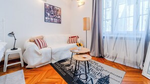 A cozy living room with a white sofa, a small side table, a lamp, and a decorative rug. - Cozy Studio in the Center of Zagreb (Zagreb)