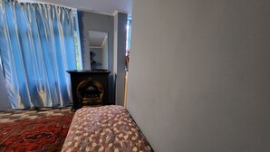 A room with a patterned bed, a fireplace, and a blue curtain. - Gabala Garden Hostel (Gabala)