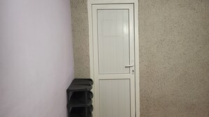 A room with a white door, a speckled wall, and a corner shelf unit. - Gabala Garden Hostel (Gabala)
