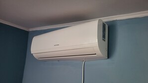 A white air conditioning unit mounted on a blue wall. - Gabala Garden Hostel (Gabala)