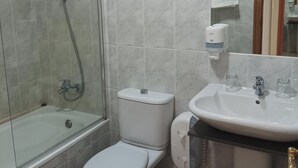 A bathroom with a glass-enclosed shower, a toilet, and a sink with two glass cups. - Hotel Villajardin (Portomarin)