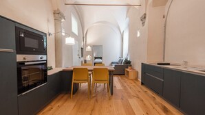 A modern kitchen with a dining area, wooden flooring, and a view into the living room. - Ramaglianti Hidden Gem by Mmega (Florence)