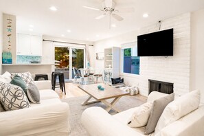 Una sala de estar moderna con chimenea, televisor de pantalla plana y comedor con vistas al exterior.