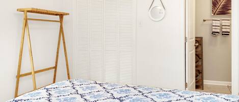 A bedroom with a bed, a wooden ladder, a white closet, and a bathroom door.